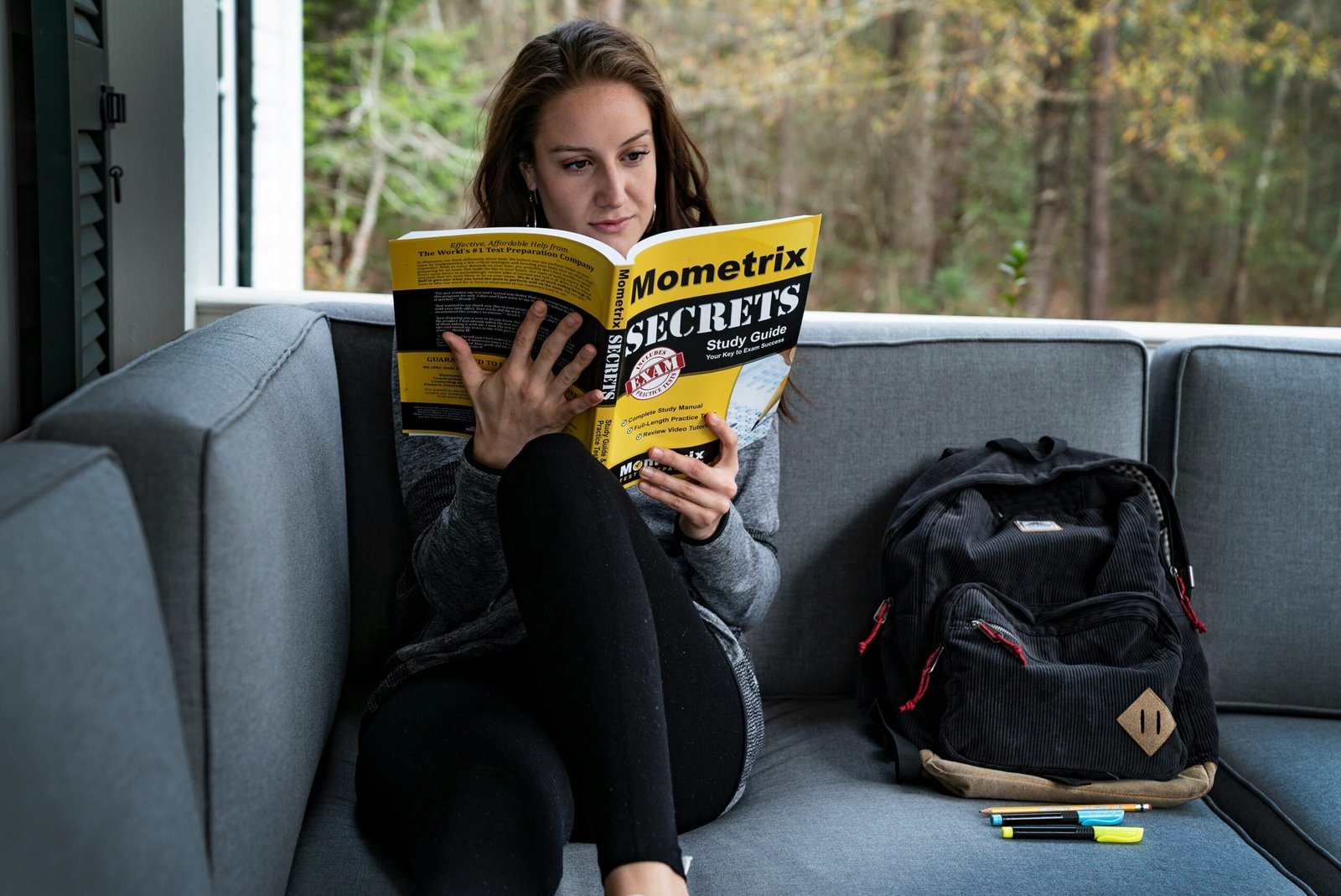 woman sitting on sofa beside bag while reading