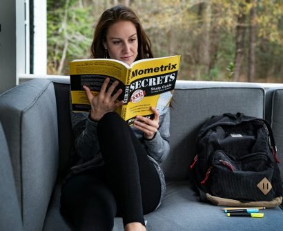 woman sitting on sofa beside bag while reading